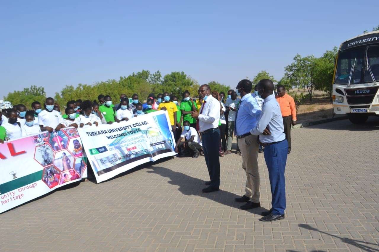Students and staff on campus with a College welcome banner