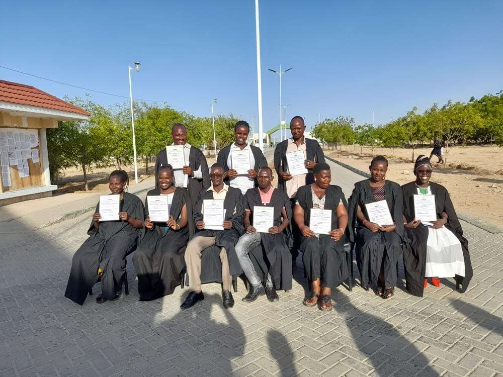 Graduates in academic gowns holding their certificates